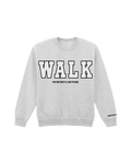 Front view of a heather grey crewneck sweatshirt displayed against a plain white background. The front features the word “WALK” in large American collegiate-style lettering. Underneath, in smaller black text, it reads: “You say shit I’ll say it back.”