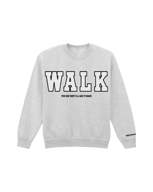 Front view of a heather grey crewneck sweatshirt displayed against a plain white background. The front features the word “WALK” in large American collegiate-style lettering. Underneath, in smaller black text, it reads: “You say shit I’ll say it back.”